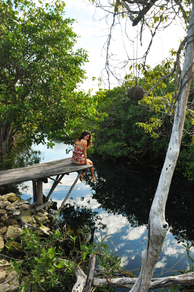 girl sitting over cenote at sunset